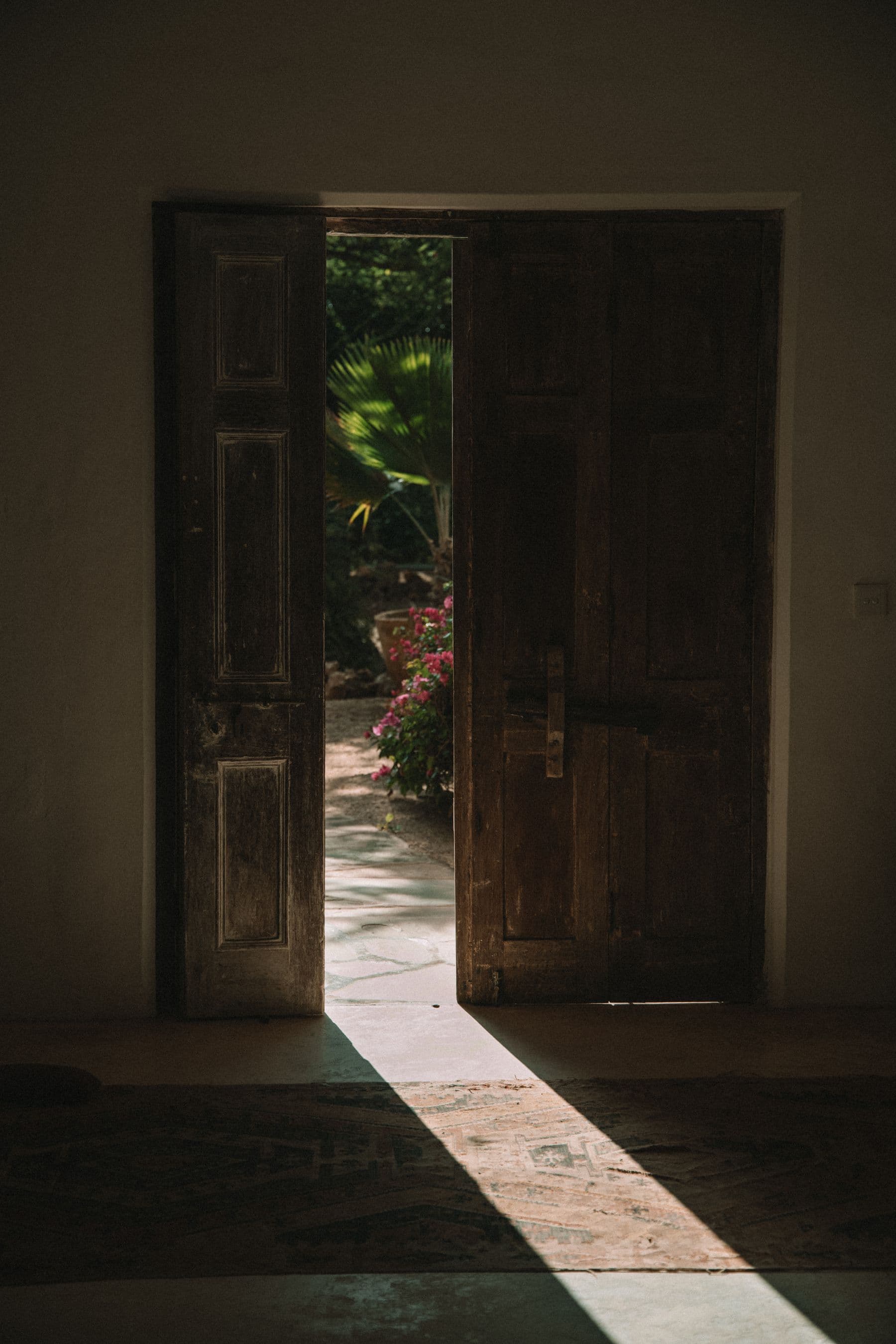 Porte ancienne en bois ouvrant sur un jardin fleuri